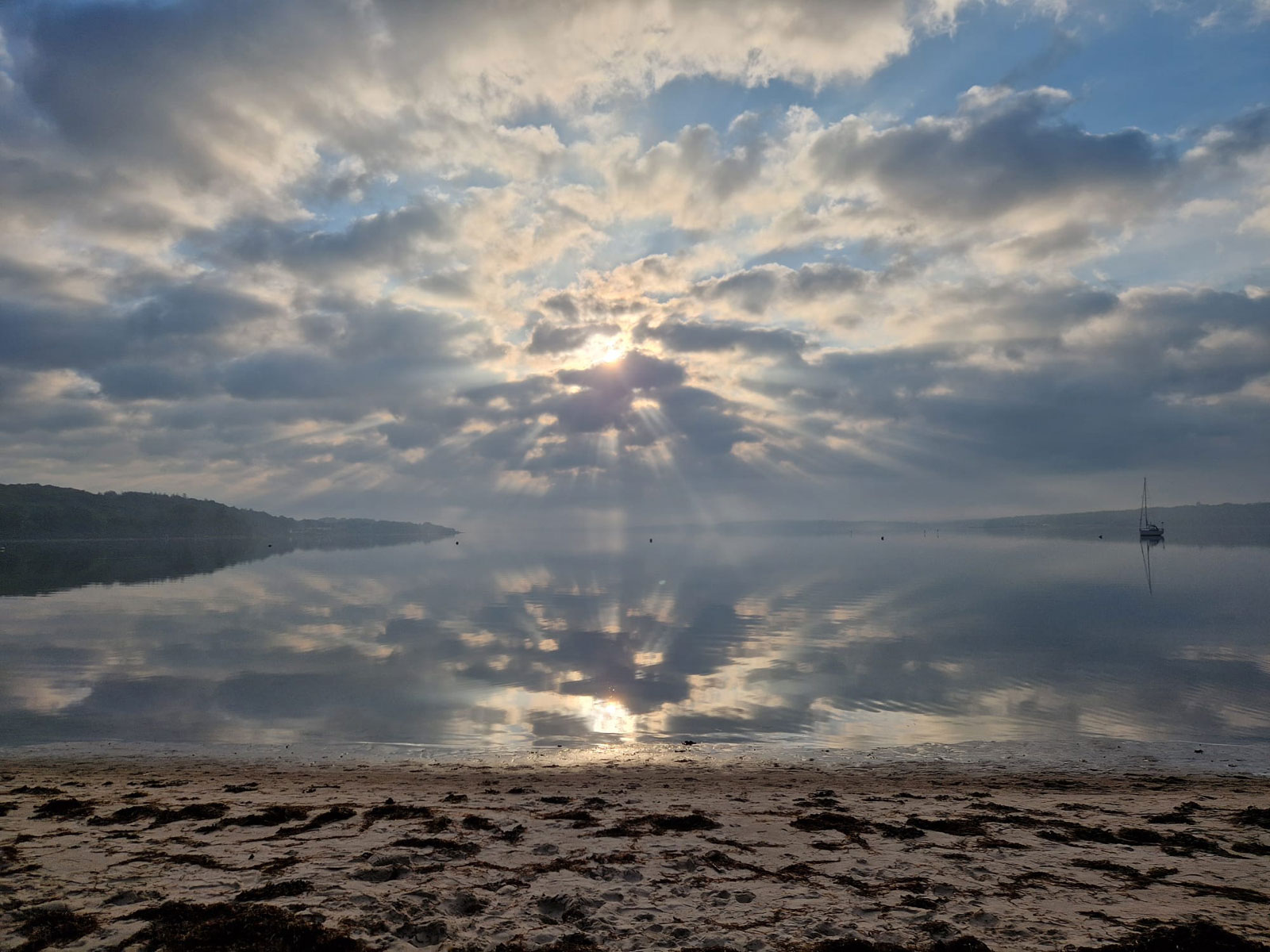 Wolkenverdeckter Sonnenuntergang über dem Meer